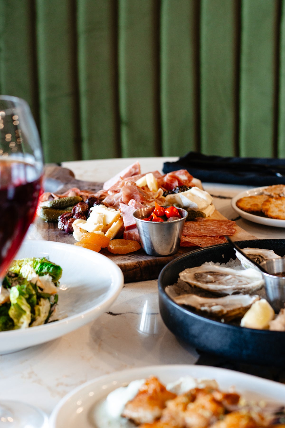 Plates of Skye Chase Estate Winery food on tabletop, including raw oysters, charcuterie, salad, and a glass of red wine.