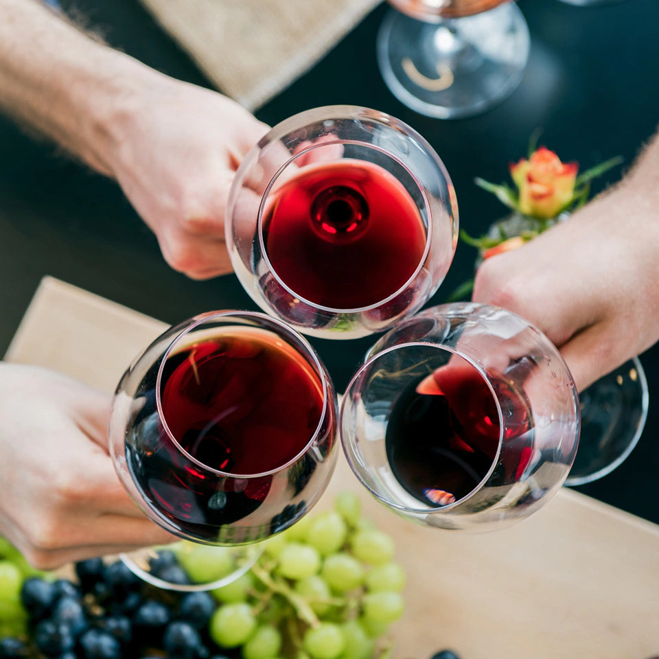 Overhead view of three wine glasses of red wine toasting